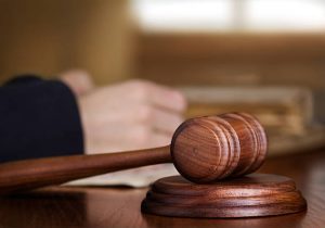 A hammer and gavel with a hand in the background